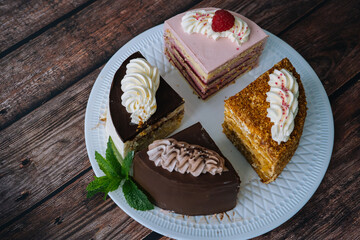 Collection of various cakes on wood background. Assortment of pieces slices with cream. Plate with different types of sweets. Several slices of delicious desserts. confectionery menu concept