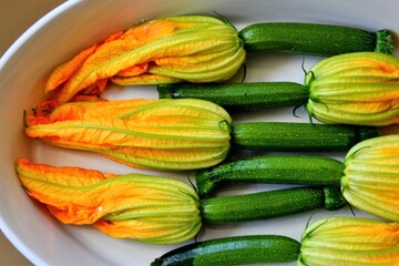 Zucchini or courgette flowers stuffed with cheese in a casserole dish. Vegan food. Ready to be baked. Selective focus, closeup. top view