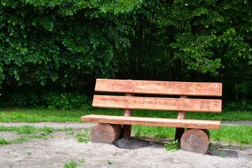Wooden bench in the forest. Bench made of wooden boards and cut tree logs. Empty bench made of tree trunks with green, forest background. Environmentally friendly. Place for text