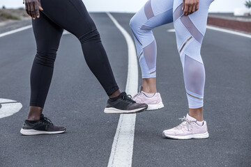 Crop diverse sportswomen bumping feet