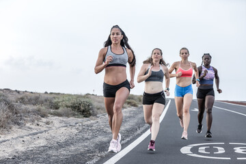 Powerful multiracial sportswomen running near roadside