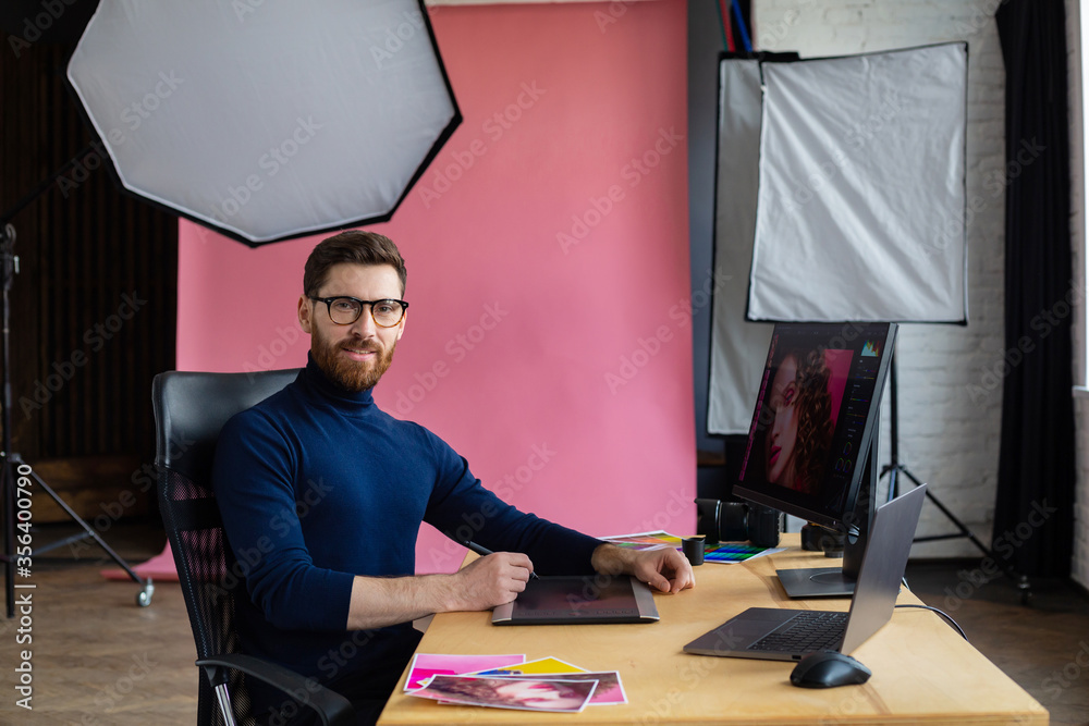 Poster Retouching images in special program.Portrait of graphic designer working in office with laptop,monitor,graphic drawing tablet and color palette.Retoucher workplace in photo studio.Creative agency.