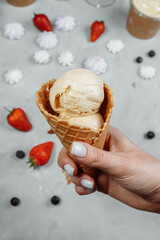 ice cream in a waffle cone on a light background in a hand. The ice cream is melting. Waffle cones...