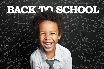 Happy black child boy student laughing on chalkboard background. Back to school concept