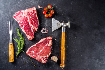 Cooking meat background. Raw aged beef t-bone steak, with spices and herbs for cooking on a gray...