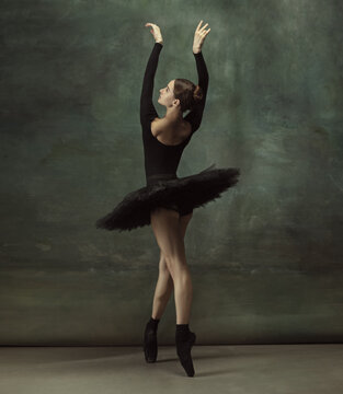 Art motion. Graceful classic ballerina dancing, posing isolated on dark studio background. Elegance black tutu. Grace, movement, action and motion concept. Looks weightless, flexible. Fashionable.