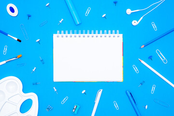 Back to School concept. Top view school supplies and stationery on a student desk on blue background. Flat lay and copy space.