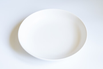 White ceramics bowl on a white backgound. Empty plate. Top view. Copy space.