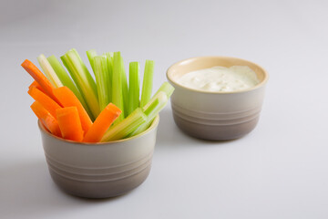 close up isolated shot of a bowl of separated crunchy orange carrot slices and juicy green celery...