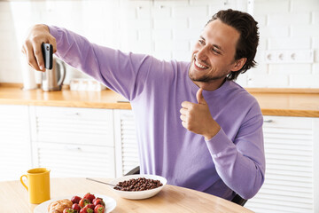 Attractive young man sitting at the kitchen table