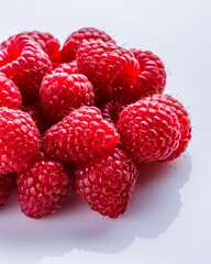 Juicy fresh natural raspberries on white acrylic background