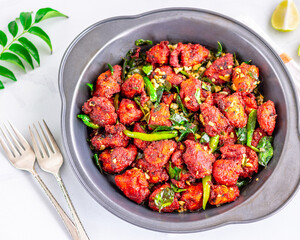 Chicken 65, Spicy Deep Fried Indian Chicken with Curry Leaves and Lemon on White Background Directly Above Photo 