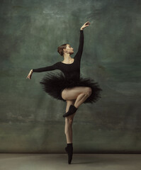 Passioned. Graceful classic ballerina dancing, posing isolated on dark studio background. Elegance black tutu. Grace, movement, action and motion concept. Looks weightless, flexible. Fashionable. © master1305