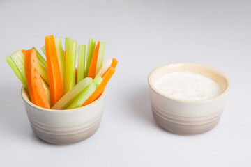 close up isolated shot of a mixed bowl of crunchy orange carrot slices and juicy green celery...
