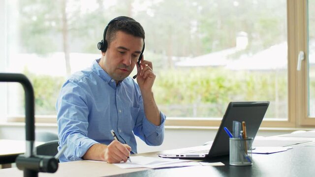 remote job, technology and business concept - middle-aged man with headset and laptop computer having conference call at home office
