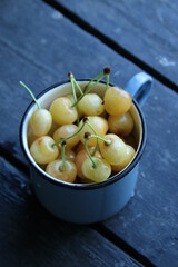 white cherries in a blue cup on a vintage table