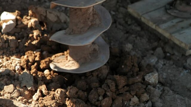 Water well drilling rig.Drill is digging a hole.Brown, clay soil.Close-up.