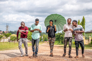 group of young african friends, walking together, laughing, having fun, using their mobile phones
