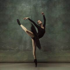 Dancing night. Graceful classic ballerina dancing, posing isolated on dark studio background. Elegance black tutu. Grace, movement, action and motion concept. Looks weightless, flexible. Fashionable.