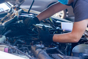Obraz na płótnie Canvas car mechanic on protective mask fixing car engine, auto mechanic is repairing car engine