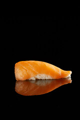 Japanese Cuisine - Appetizing Salmon Sushi Set, Nigiri. Philadelphia Sushi Roll - Maki Sushi with Philadelphia Cheese inside on mirror black background. Smoked salmon rolls served on a plate