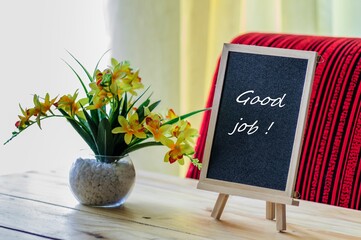 Image of motivational greeting good job on chalk board. Besides a decorative green plant in vase. Selective focus on notice board. Others in gradient blur.