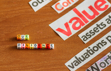 Conceptual image of due diligence over wooden surface. Spelt using colorful letter beads with common business-related title from newspaper cuts. Selective focus on beads only.