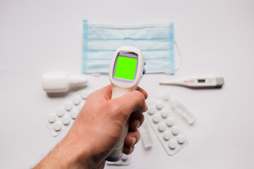 electronic thermometer in hand with medical mask