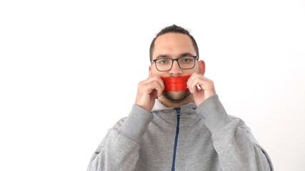 Caucasian man seals his mouth with tape in protest. Portrait of a man with tape on mouth over white background. Prohibition of freedom of speech. Silence