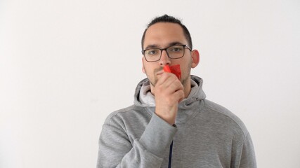 Caucasian man seals his mouth with tape in protest. Serious man looking at the camera and tearing red tape from her mouth. Prohibition of freedom of speech. Silence