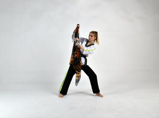 Fototapeta na wymiar beautiful girl in a white-black suit does exercises with a battle ax and a scarf