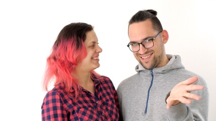 Man and woman are actively talking. Man explains a thought to a woman and shows his open palm towards the camera. Modern hipster family. Wife with pink hair and husband with ponytail