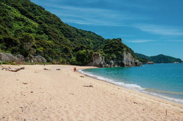 Couple on the beach in front of a cliff at Abel Tasman National Park. Anapai Bay.