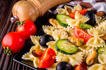 Delicious pasta salad with tomato cucumber and olives on wooden rustic background