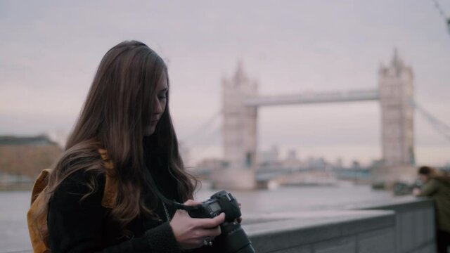Tourist Woman Going Through Photos on Camera with Tower Bridge in The Background