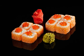 Japanese Cuisine - Appetizing Salmon Sushi Set. Philadelphia Sushi Roll - Maki Sushi with Philadelphia Cheese inside on mirror black background. Smoked salmon rolls served on a plate