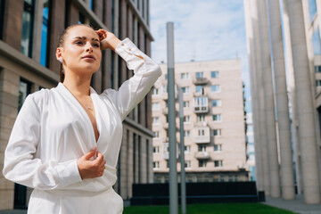 Fototapeta premium Elegant young girl in the background of the business center on a summer day. The concept of an elite construction company
