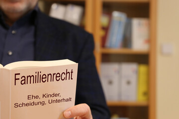 Symbolbild: Anwalt für Familienrecht hält ein Buch in der Hand