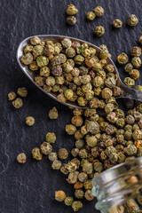 green peppercorns on dark slate stone background