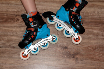 Roller skates on the child's feet on a wooden background.
