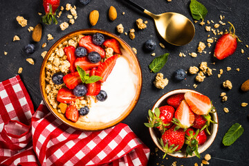 Greek yogurt granola with fresh berries on black stone table.