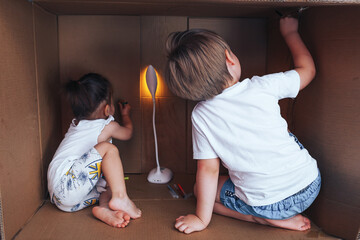 Fototapeta premium Beautiful little children draw with felt-tip pens and play in box, activity for children at home