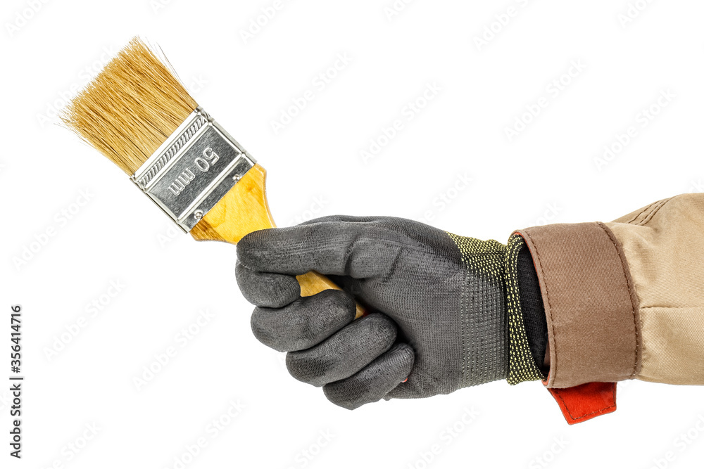 Wall mural unused construction paintbrush in worker hand in black protective glove and brown uniform isolated o