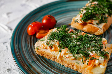 A couple of vegetable sandwiches on fresh white bread with cheese, carrots and crab meat, decorated with dill greens, next to cherry tomatoes and a fragrant garlic smell of snacks