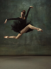 Balanced. Graceful classic ballerina dancing, posing isolated on dark studio background. Elegance...