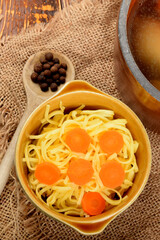 a clay pot full of chicken broth next to a bowl of cooked pasta