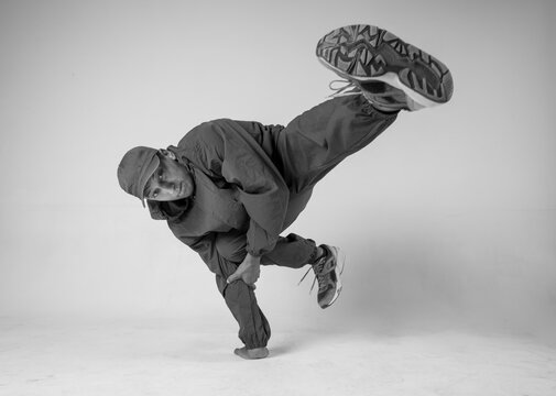 A man hip hop dancer or bboy freezes in one pose on a white background. Bboy doing stylish stunts.