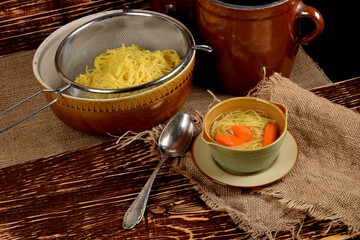 delicate carrot broth in a small bowl next to clay pots