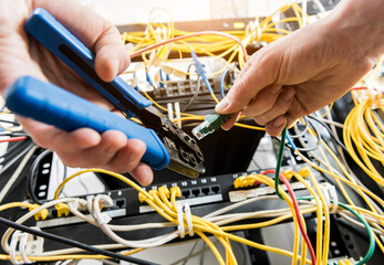 Network engineer working in server room. Connecting network cables to switches