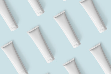 Mockup white plastic tubes pattern for cosmetic product. Containers for hand cream, moisturizer body lotion, facial cleanser or shampoo on pastel blue background, above